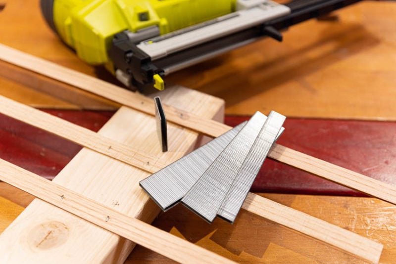 Carpenter Using an Industrial Construction Stapler on a Wood Plank