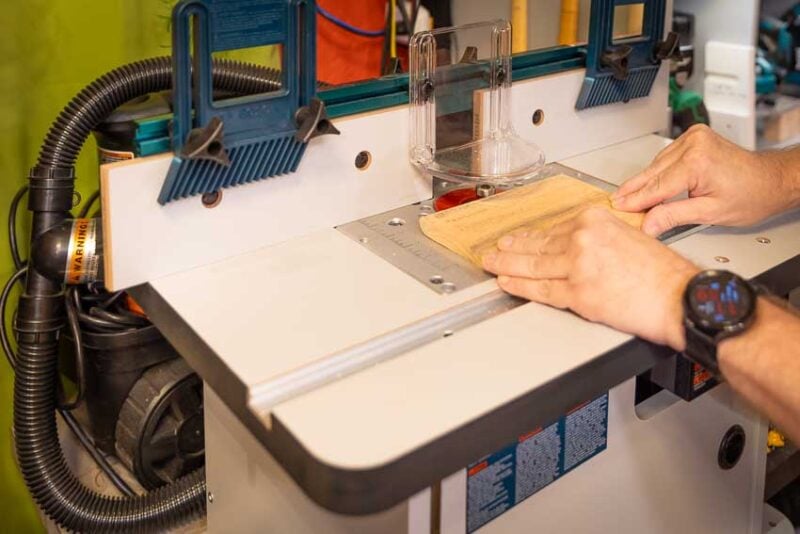 Adding a 3/8-inch round over to a small wood base. While you could do this on a router, it is much safer to do it on the router table because of the small size of the part.